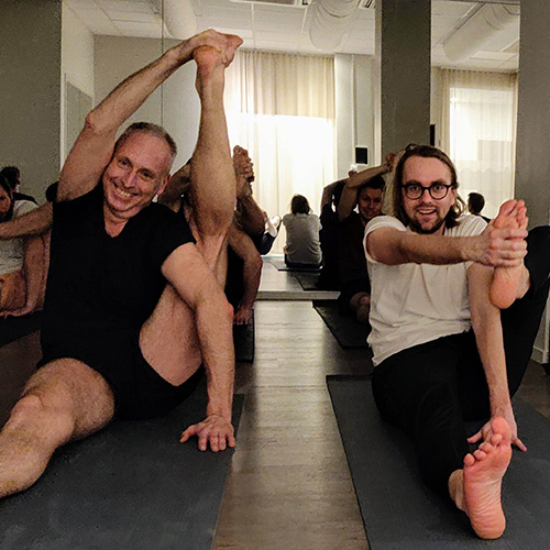 Två glada män på en yogaklass